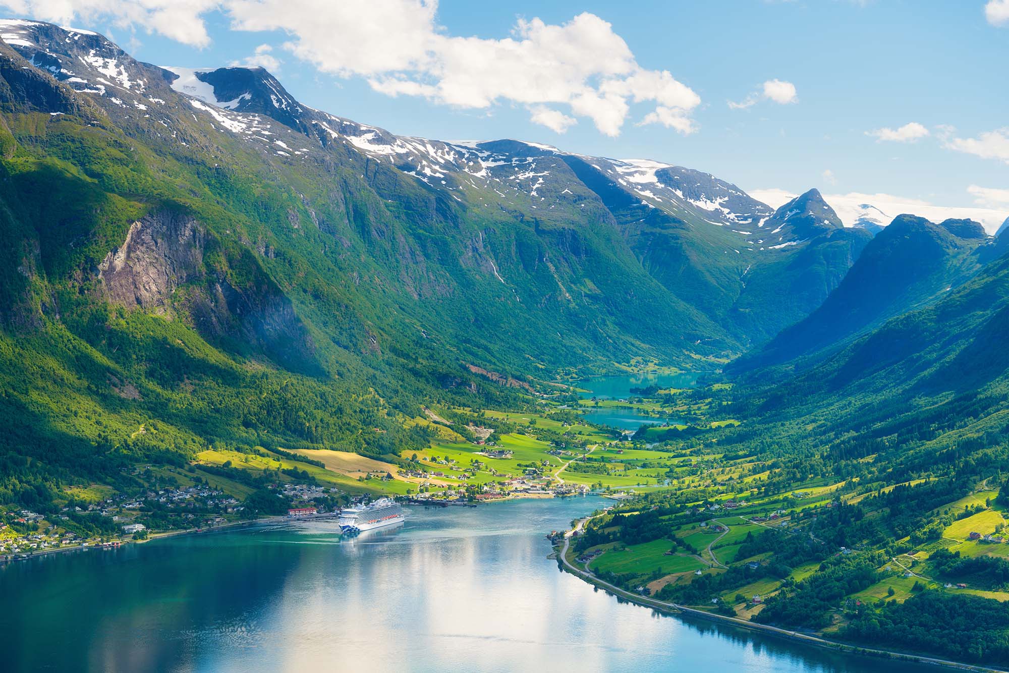 Norway. Cruise ship in the Norwegian fjord. High mountains and reflections on the surface of the water. Clouds over the rocks. Vacation and travel in summer Norway.