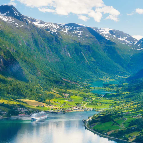 Norway. Cruise ship in the Norwegian fjord. High mountains and reflections on the surface of the water. Clouds over the rocks. Vacation and travel in summer Norway.
