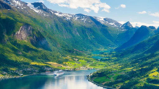 Norway. Cruise ship in the Norwegian fjord. High mountains and reflections on the surface of the water. Clouds over the rocks. Vacation and travel in summer Norway.