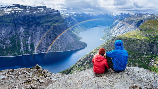 Couple looking at a double rainbow over the Norwegian Fjords