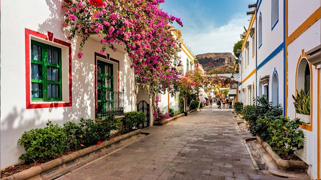 Street with blooming flowers in Puerto de Mogan, Gran Canaria, Spain. Favorite vacation place for tourists and locals on island. Puerto de Mogan with lots of bougainvillea flowers, Canary Island.
