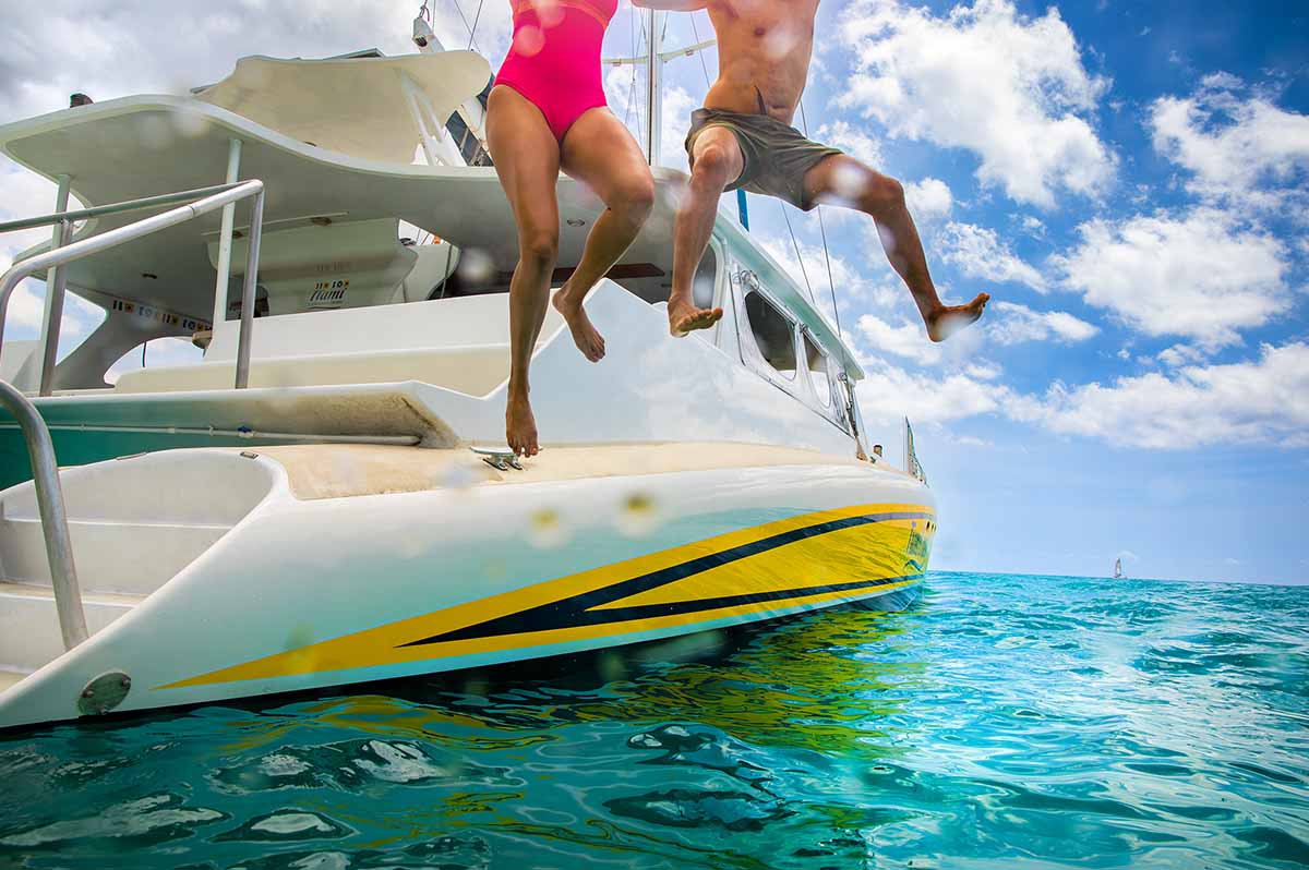 Couple jumping off a Catamaran