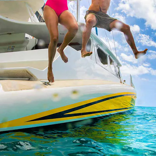 Couple jumping off a Catamaran