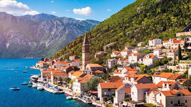 View of the historic town of Perast at famous Bay of Kotor on a beautiful sunny day with blue sky and clouds in summer, Montenegro. Historic city of Perast at Bay of Kotor in summer, Montenegro.