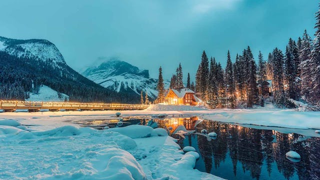 Beautiful winter scene of wooden lodge glowing on Emerald Lake and pine forest at Yoho national park, British Columbia, Canada