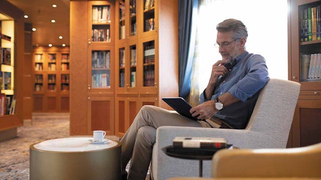 Passenger taking a moment in the Libary on Seven Seas Splendor