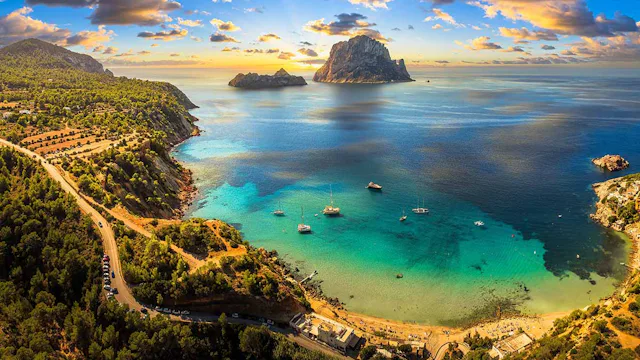 Aerial view of Cala d’Hort beach in Ibiza, featuring the iconic Es Vedrà rock, turquoise waters, and scenic Mediterranean coastline.