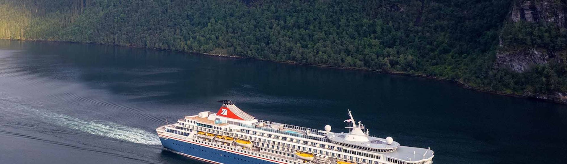 Fred Olsen Balmoral Cruise Ship sailing through a green valley