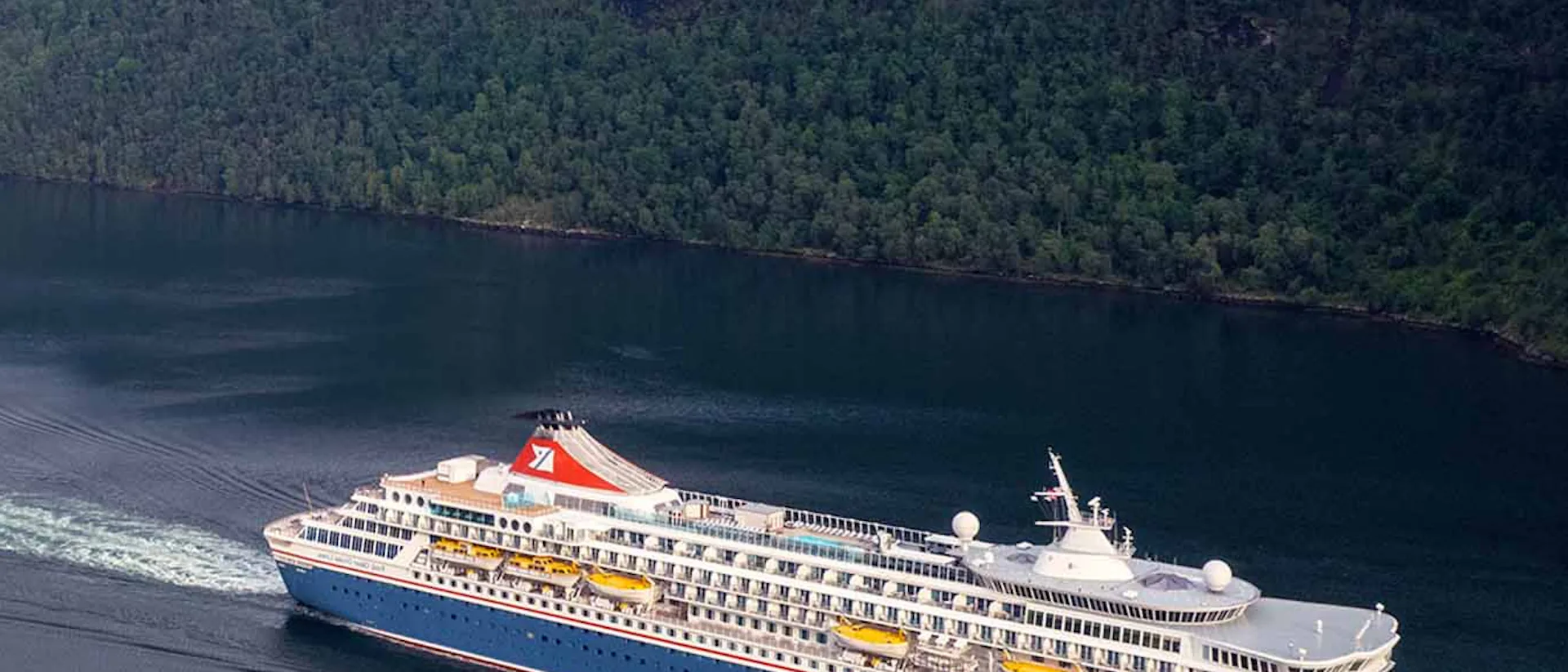 Fred Olsen Balmoral Cruise Ship sailing through a green valley